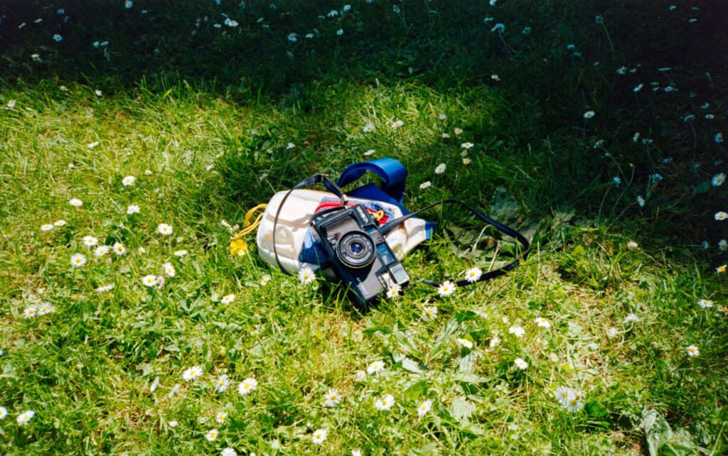 Photograph of a Minolta Himatic AF2-M in a field of grass, taken with a film camera